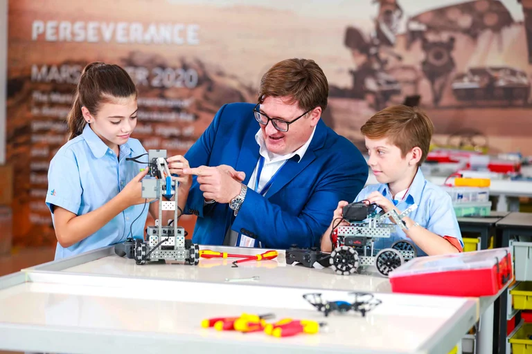 students and teacher building a machine