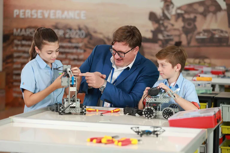 students and teacher building a machine