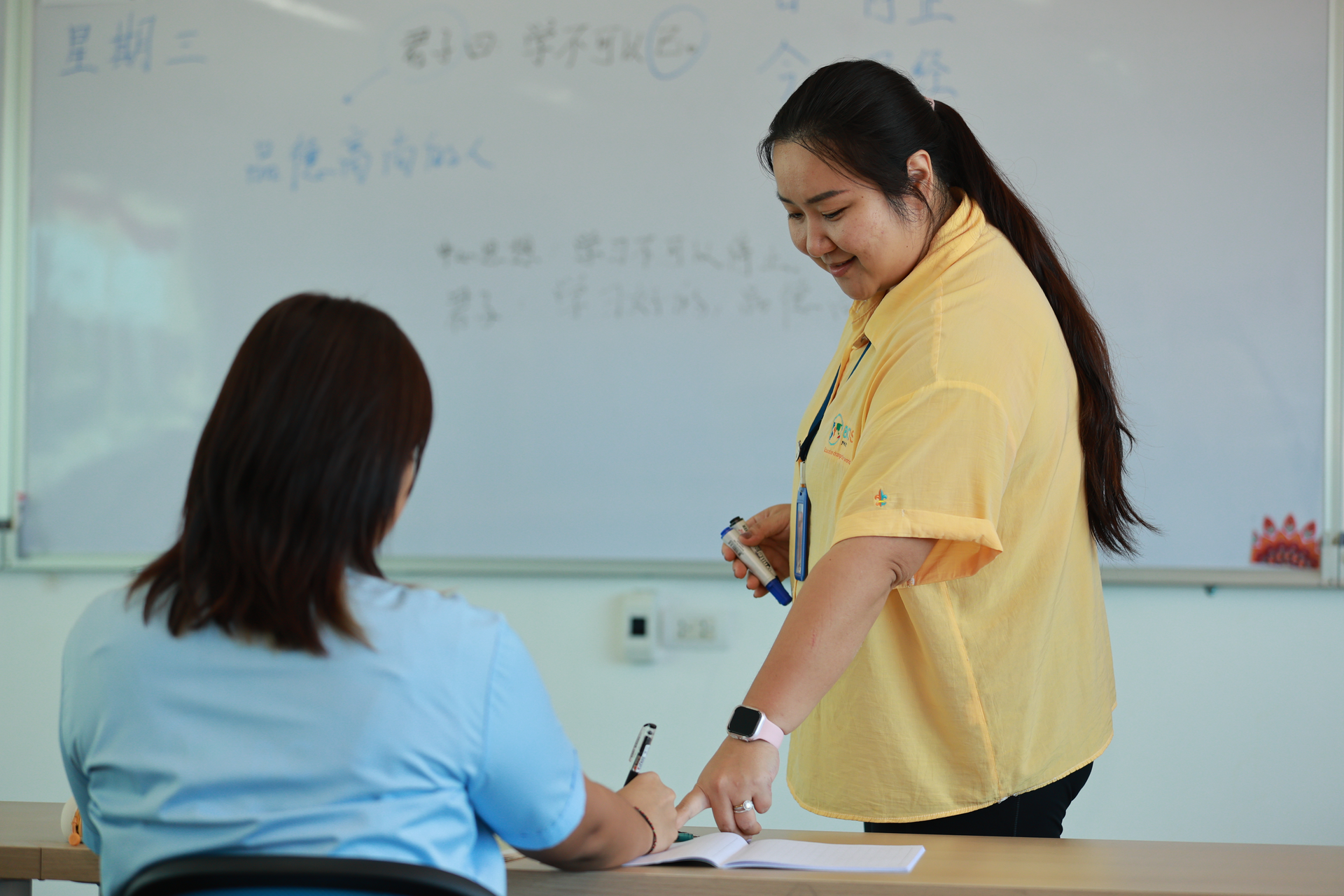 teacher pointing a book to a student
